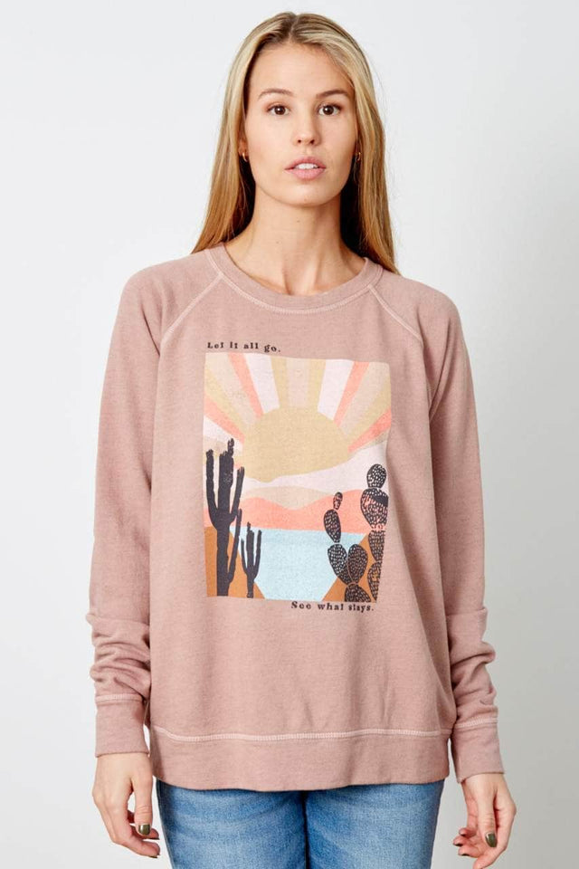 Model wearing blush pink, relaxed fit, crewneck sweatshirt with graphic on front
