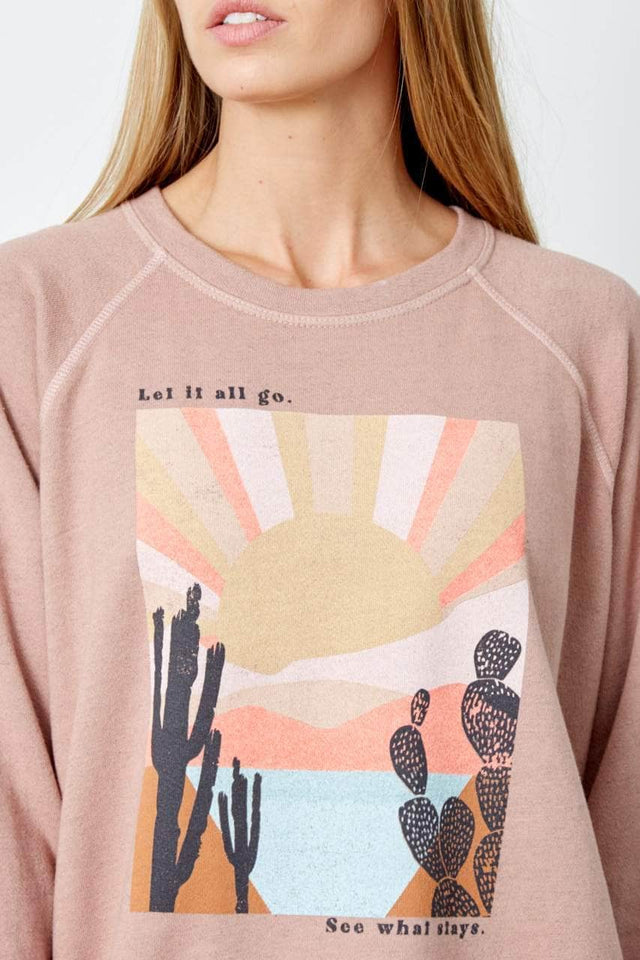 Model wearing blush pink, relaxed fit, crewneck sweatshirt with graphic on front